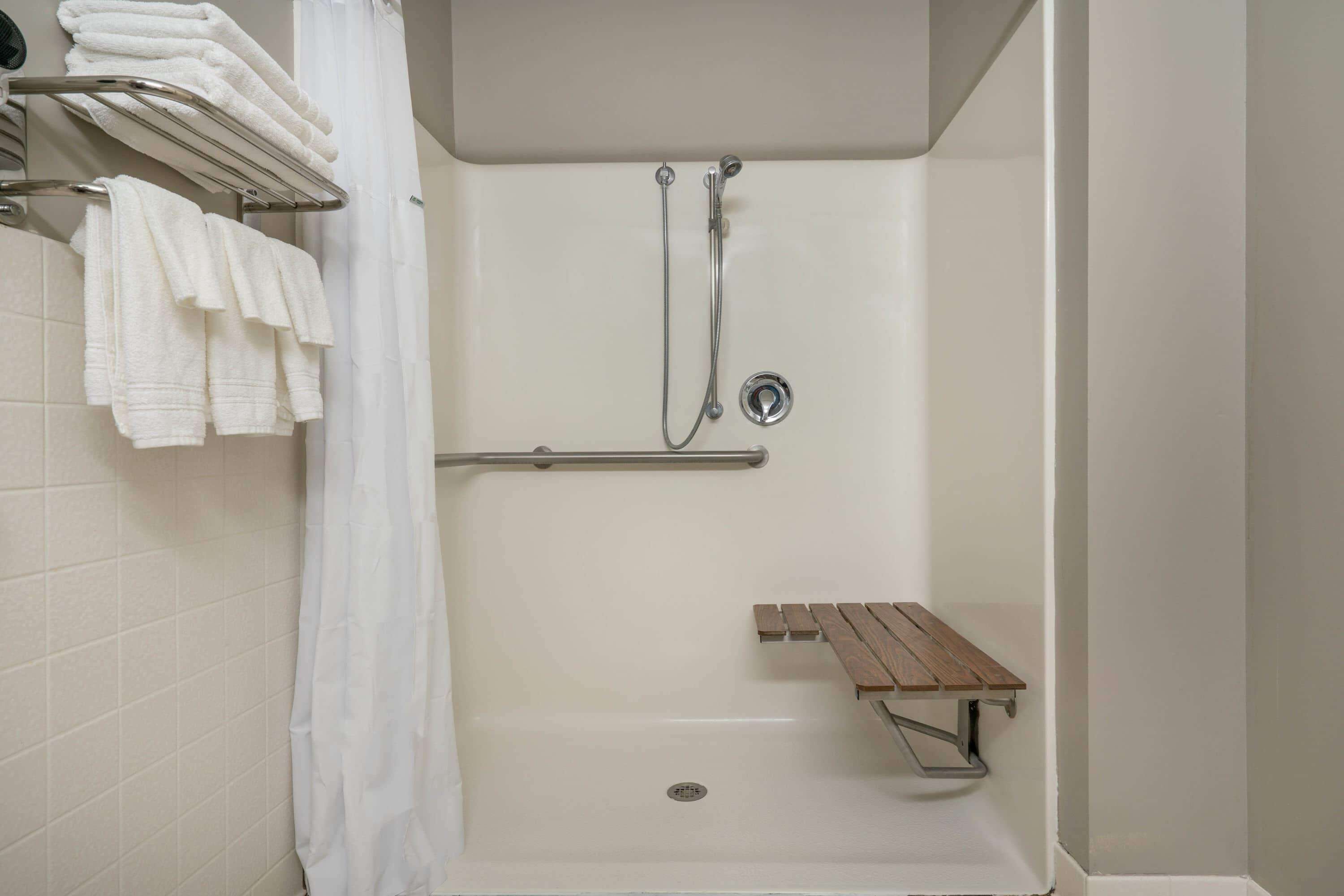 Un espace douche équipé d’un banc, d’un porte-serviettes et d’un pommeau de douche.