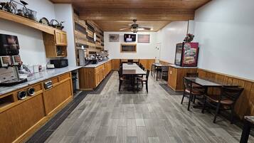 Une cuisine dotée de meubles en bois, d’un îlot central et d’un coin repas avec des tables et des chaises.