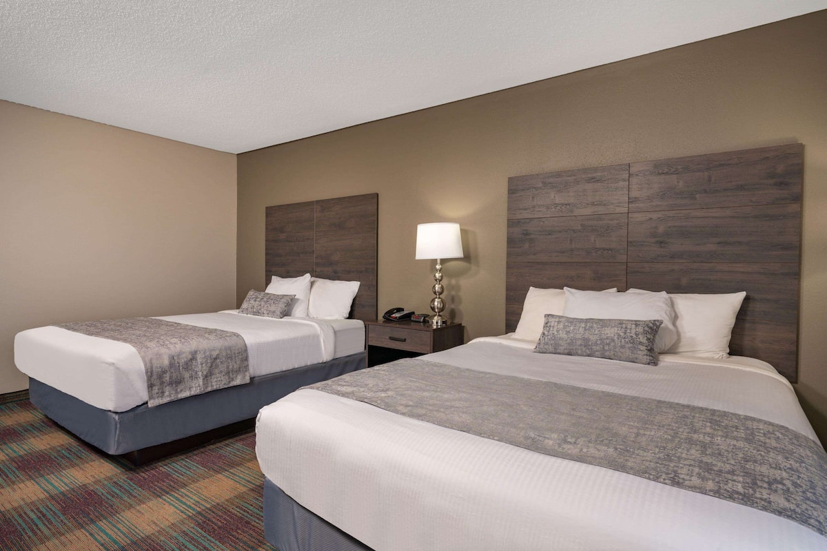 A hotel room with two beds, a nightstand, a lamp, and a telephone.
