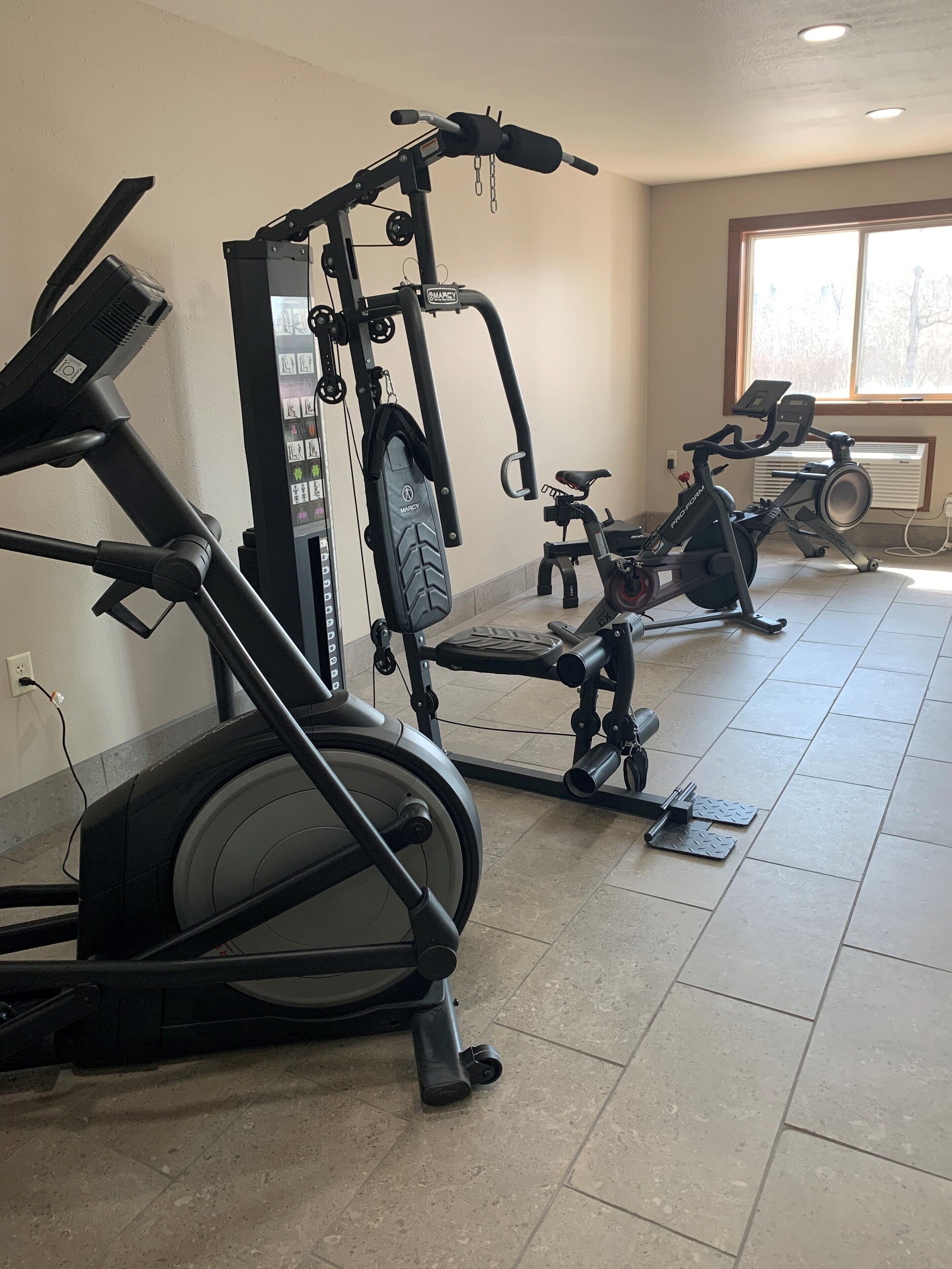 A home gym with stationary bikes, a treadmill, and a weight machine.