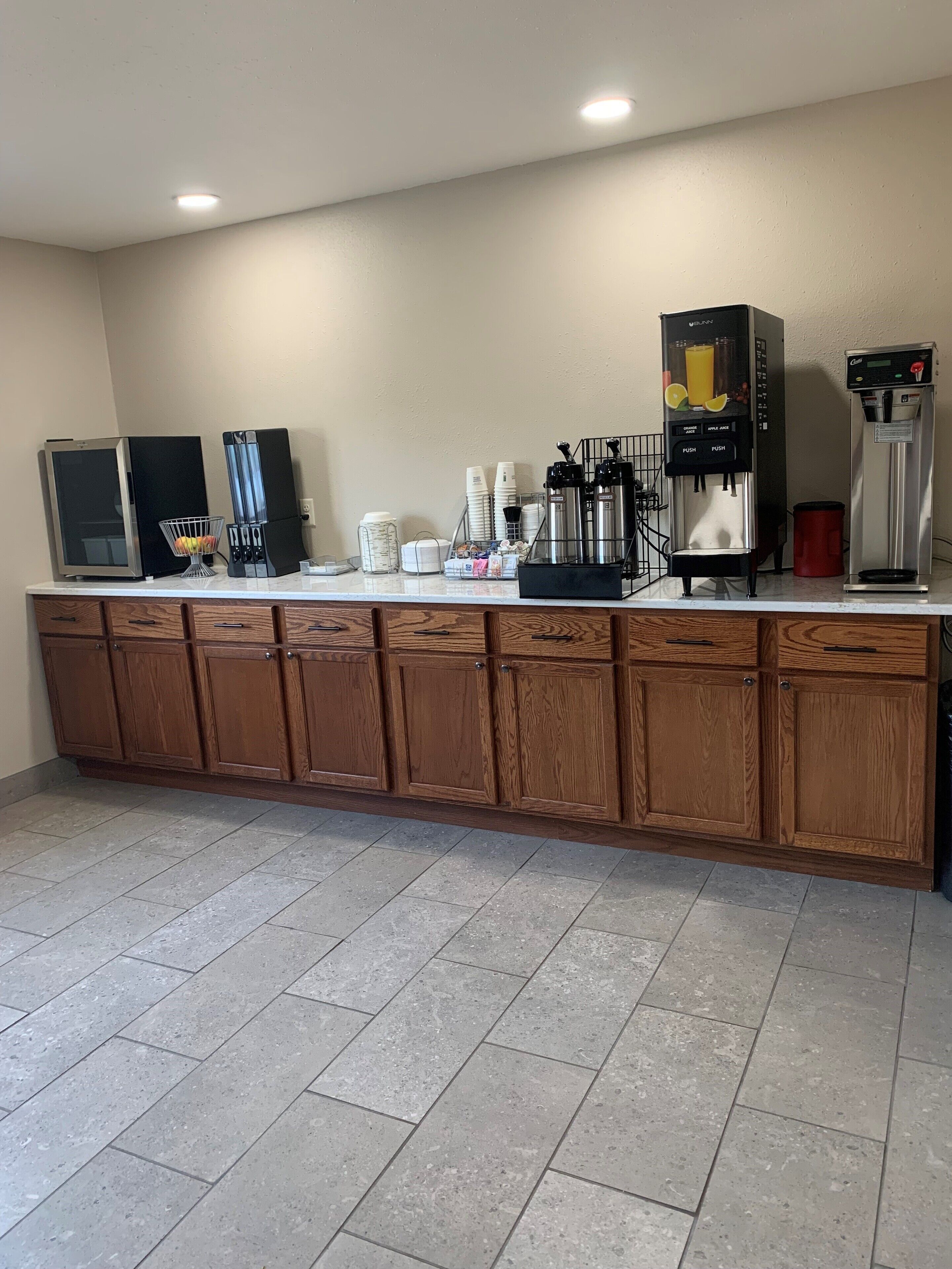 Una kitchenette equipada con refrigerador, cafetera y dispensador de jugo.