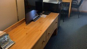 Une chambre d’hôtel avec un bureau en bois, une télévision, une lampe, une chaise et un lit.