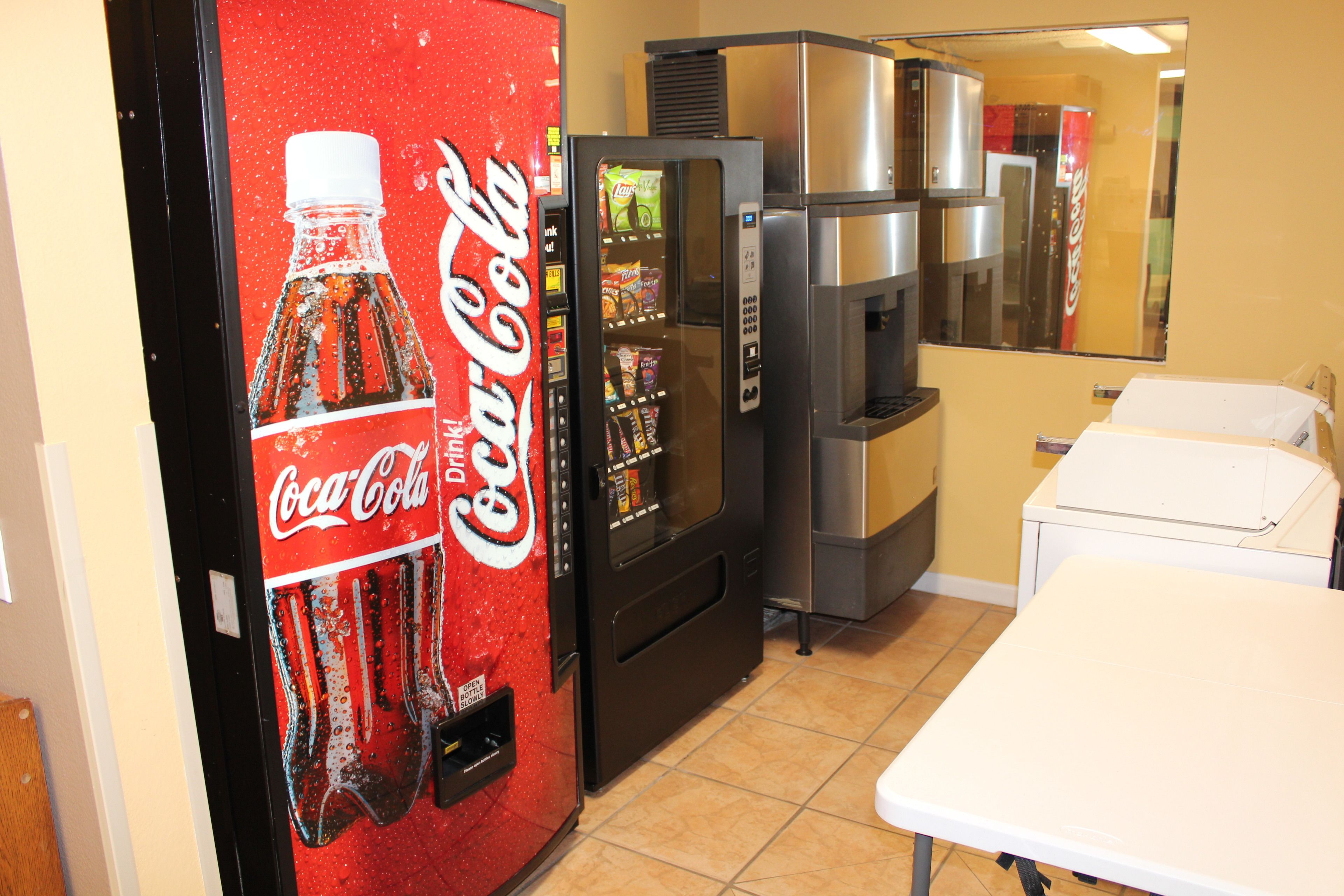Una cocina con una máquina expendedora de Coca-Cola, un refrigerador y un microondas.
