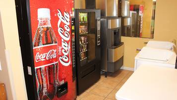 Una cocina con una máquina expendedora de Coca-Cola, un refrigerador y un microondas.