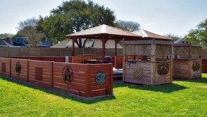 Une structure de jeu en bois dotée d’un espace de repos abrité et d’une zone délimitée par une clôture.