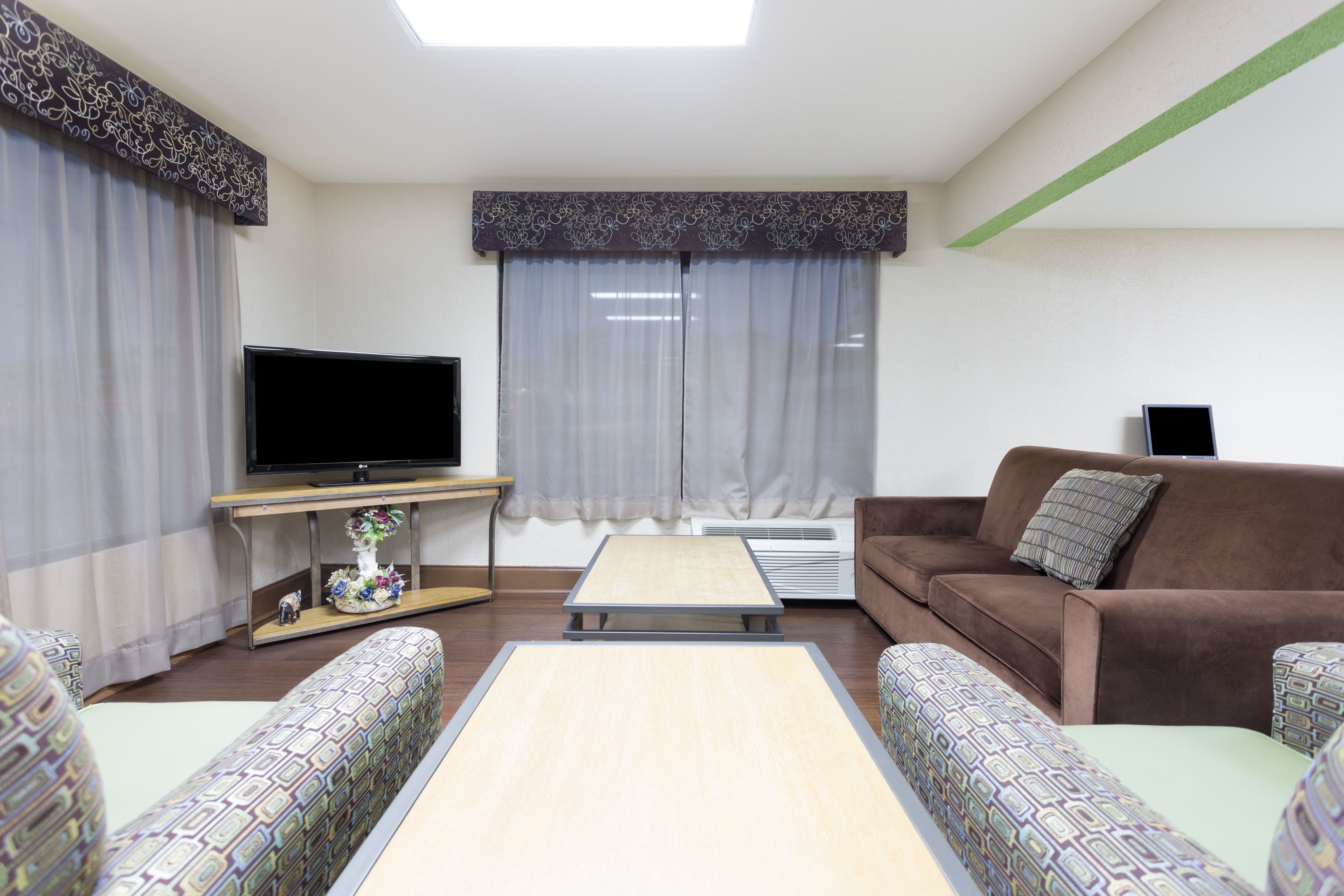 A living room with a sofa, a television, a coffee table, and patterned cushions.