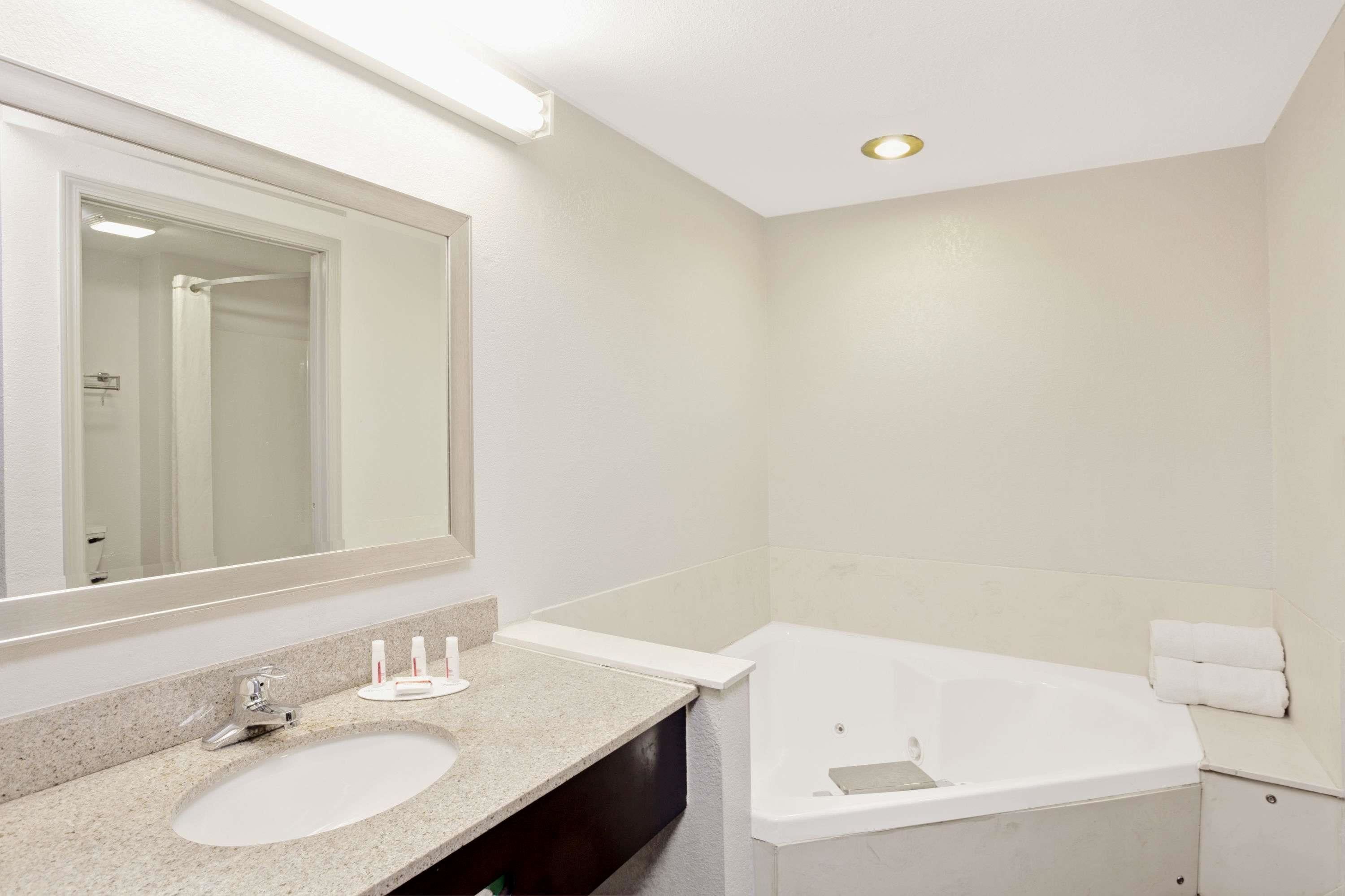 A bathroom with a sink, mirror, and bathtub.