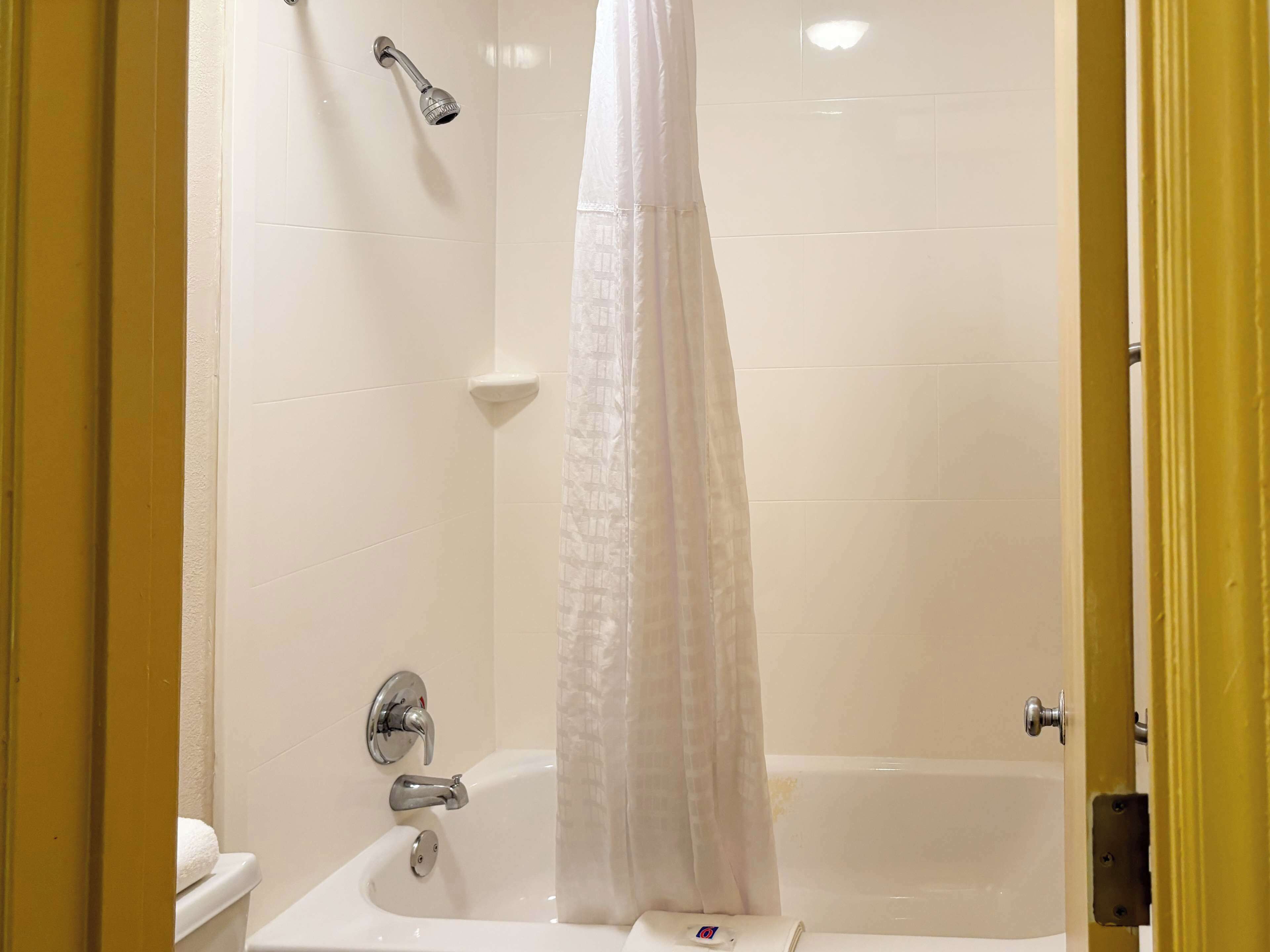 A bathroom with a bathtub, a showerhead, and a toilet.