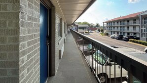 A balcony with a view of a parking lot and a building with multiple floors. - Motel 6 Charlotte, NC - Northlake (Charlotte)