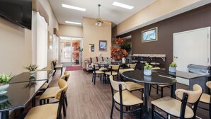 A conference room with glass tables and chairs, a ceiling fan, and a large window with blinds.