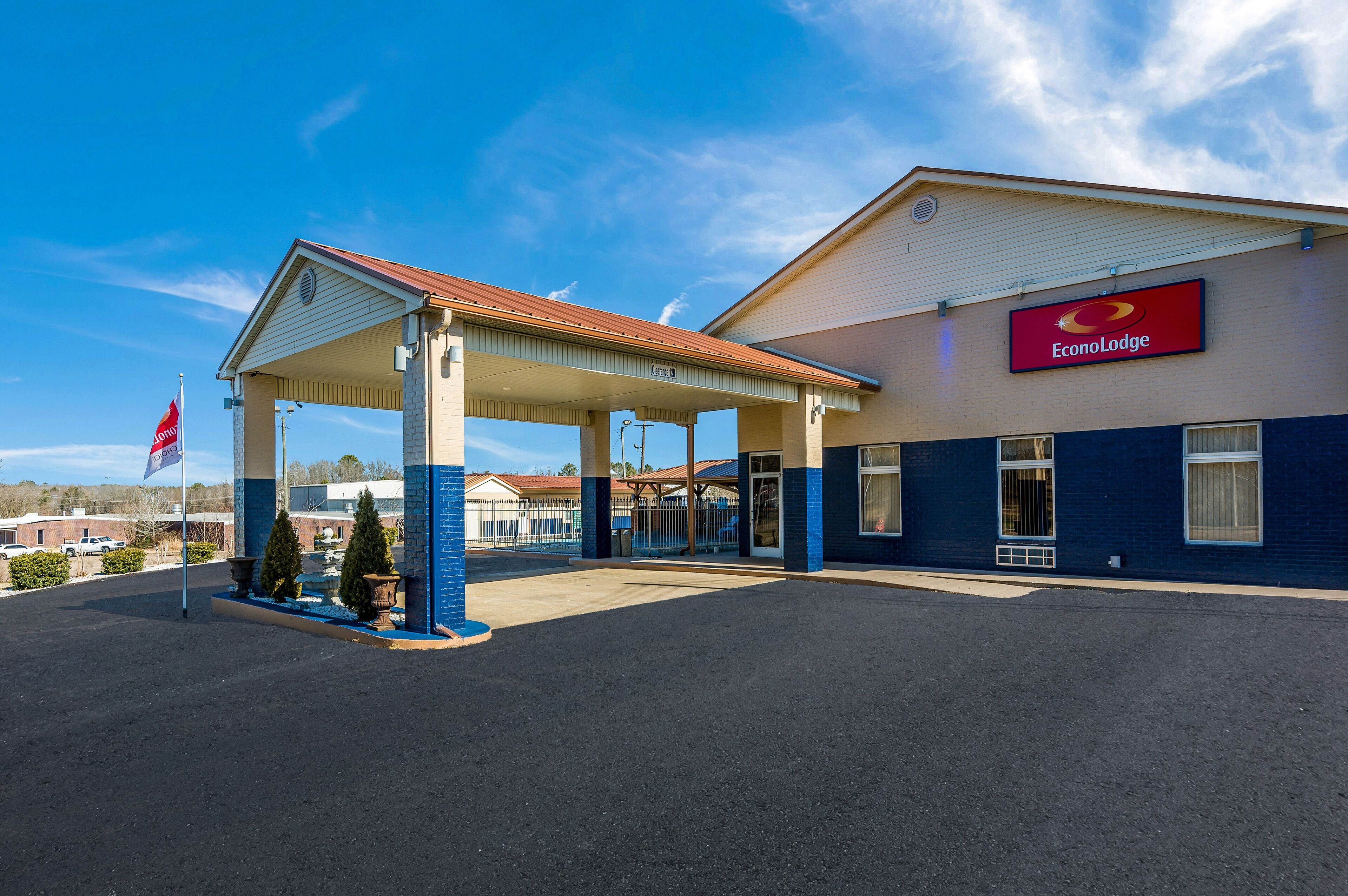 A hotel with a covered outdoor area, a flag, and a clear blue sky.