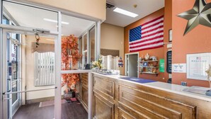 A reception area with a wooden counter, an American flag, and a welcome sign.