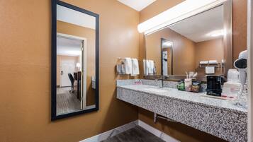 A bathroom with a granite countertop, a large mirror, and a hairdryer.
