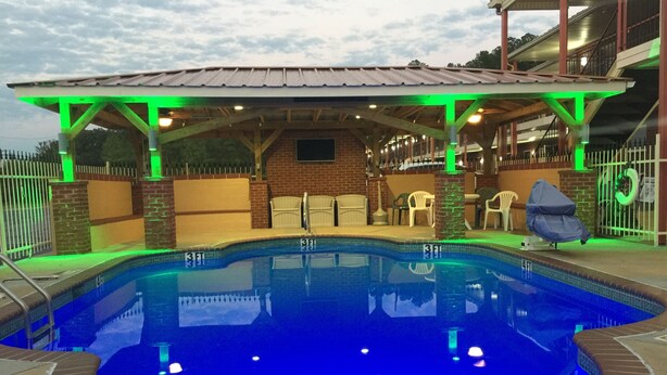 A swimming pool with a covered area, a brick wall, and a gated entrance.