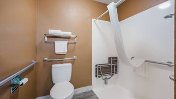 A bathroom with a white toilet, a shower with a white curtain, and a towel rack with two towels.