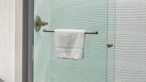 Un baño con pared texturizada, una toalla colgada en un perchero metálico y una puerta con picaporte metálico.