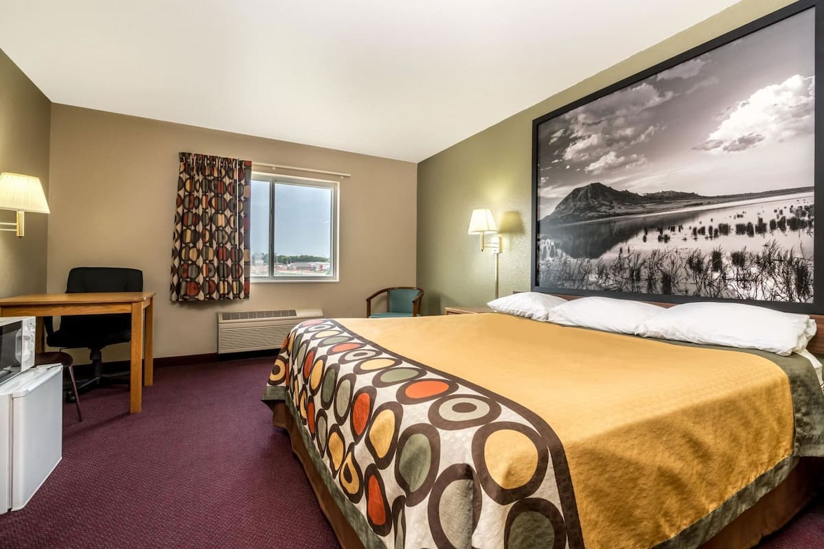 Ein Hotelzimmer mit Bett, Schreibtisch, Stuhl und einem großen Fenster.