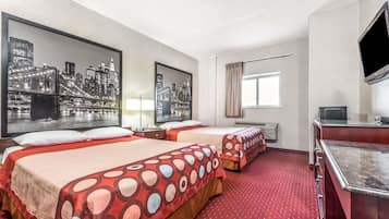 A hotel room with two beds, a desk, a TV, and cityscape artwork on the walls.