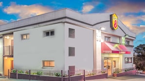 A hotel with a 'Super 8' sign, a lobby entrance, and a clear sky. - Super 8 by Wyndham North Bergen NJ/NYC Area (North Bergen)