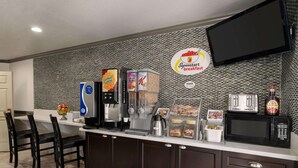 Una barra de desayuno con máquina de café, dispensadores de cereales y microondas.