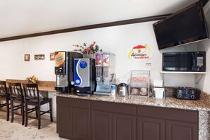 A kitchen with a coffee machine, a toaster, a microwave, and a breakfast sign. - Super 8 by Wyndham Santa Clarita/Valencia (Canyon Country)