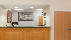 A reception area with a wooden counter, a framed welcome sign, a phone, and a door.