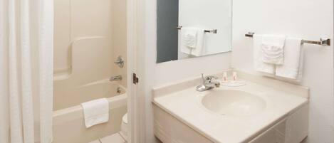 A bathroom with a bathtub, a sink, a mirror, and a towel rack.
