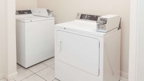 A laundry room with two white washing machines and a dryer.