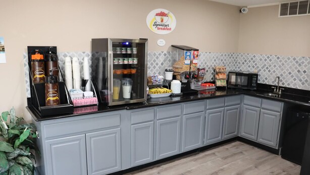 A breakfast bar with a coffee machine, refrigerated drinks, and a variety of food items. - Super 8 by Wyndham Cabot (Cabot)