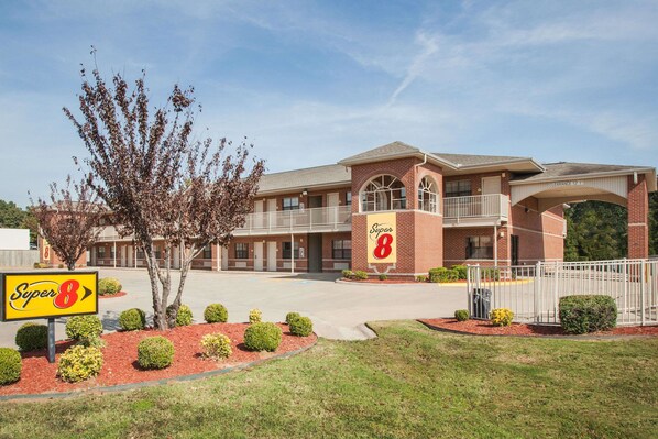 A Super 8 motel with a brick facade, multiple balconies, and a clear sky. - Super 8 by Wyndham Cabot (Cabot)