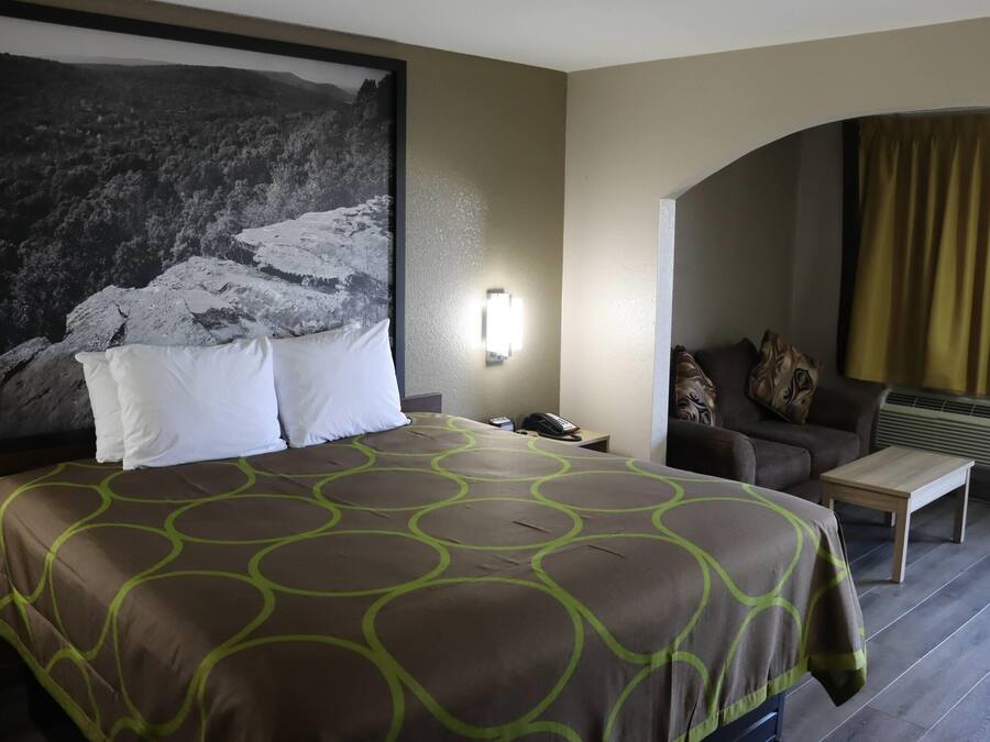 Ein Hotelzimmer mit einem großen Bett, einer Couch, einem kleinen Tisch und einer Wandlampe.