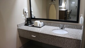 A bathroom with a granite countertop, a white sink, a mirror, a hairdryer, and a coffee maker. - Super 8 by Wyndham Cabot (Cabot)