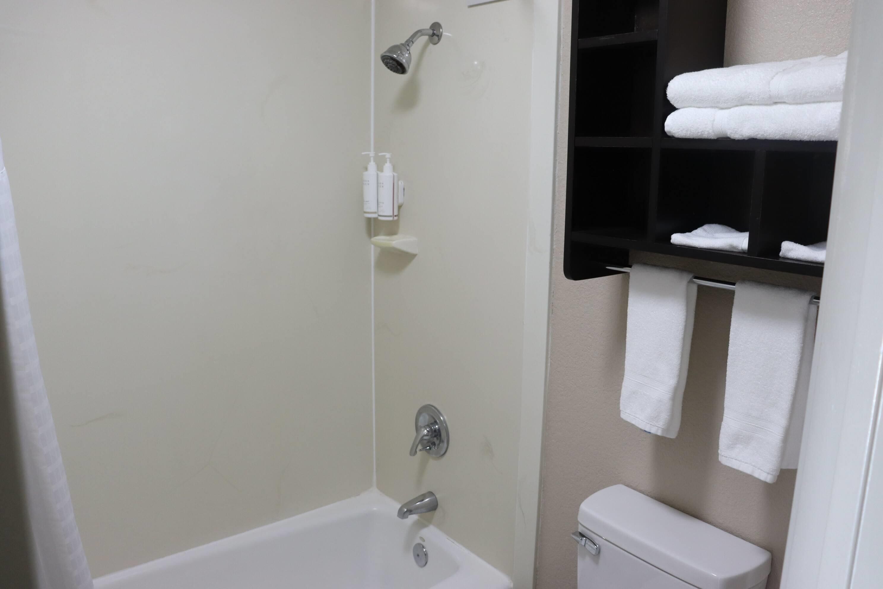 A bathroom with a bathtub, toilet, and towel rack.