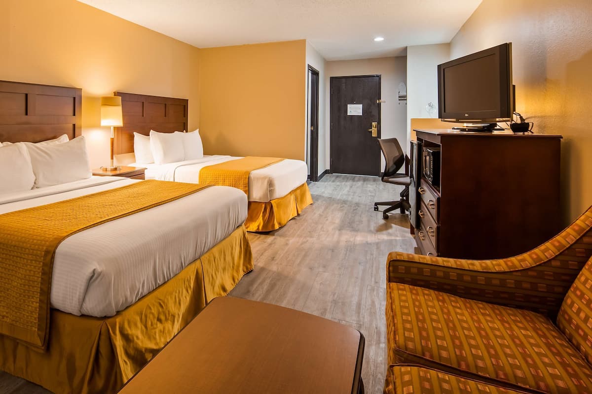 Une chambre d’hôtel avec deux lits, un bureau, une chaise et un téléviseur.