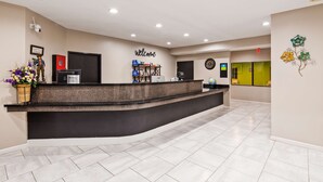 A hotel reception area with a curved reception desk, a 'Welcome' sign, a clock, a globe, and a 'Rewards' sign. - SureStay Hotel by Best Western Orange (Orange)
