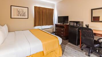 Una habitación de hotel con una cama, un escritorio con computadora, televisor y microondas.