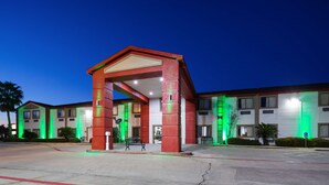 A hotel entrance with a red archway, multiple floors, and green exterior lighting. - SureStay Hotel by Best Western Orange (Orange)