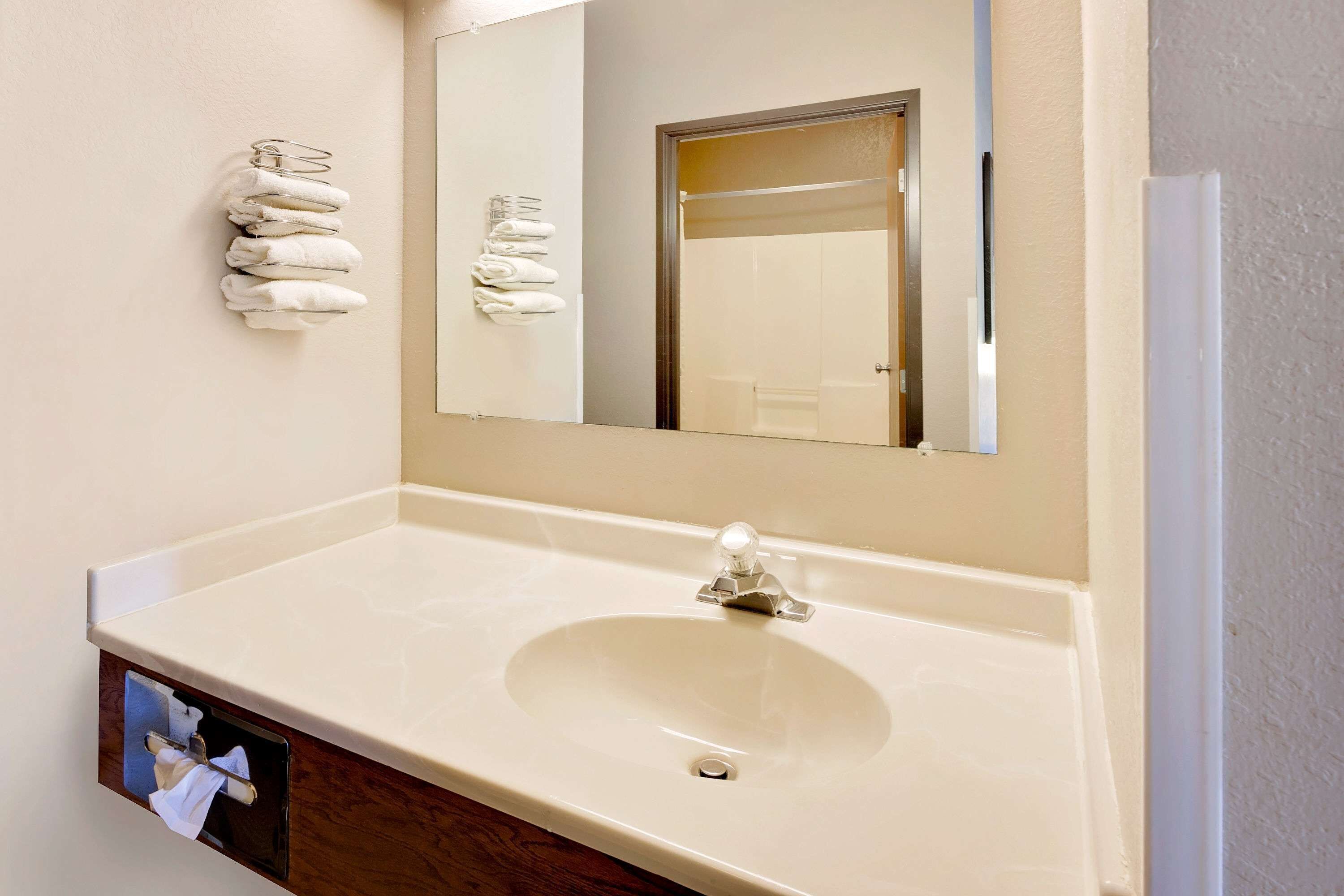 A bathroom with a white sink, a mirror, and a towel rack.