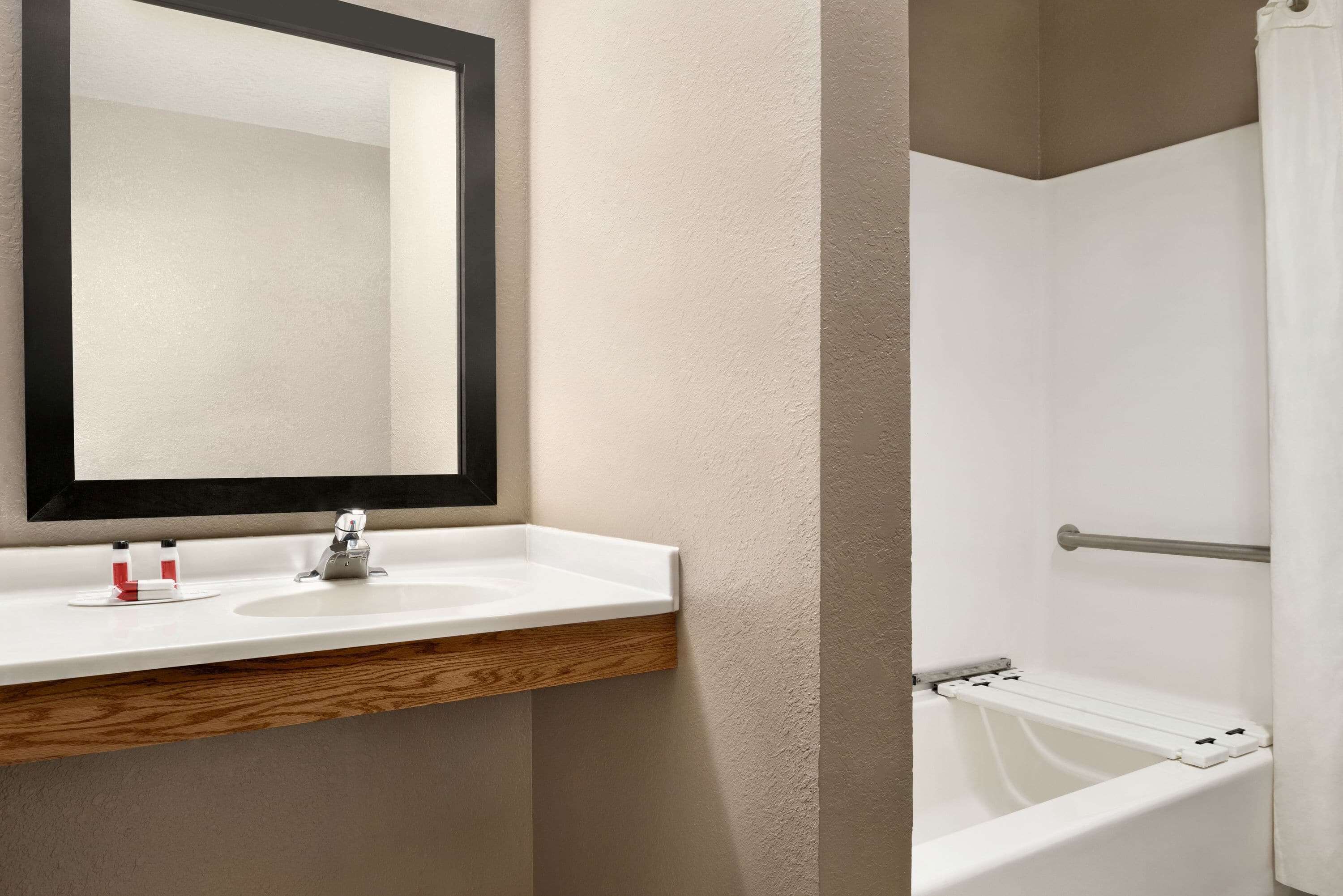 A bathroom with a white sink, a mirror, and a bathtub.
