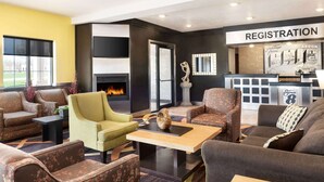 Un vestíbulo de hotel con una mesa de recepción, sofás, una chimenea y un ventanal grande.