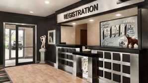Un mostrador de registro con un letrero que dice 'REGISTRATION', un cartel de bienvenida enmarcado y una estatua de un caballo.