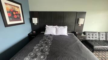 Hotelkamer met een groot bed, twee nachtkastjes, een hoofdeinde, een bank en een aan de muur hangend schilderij.