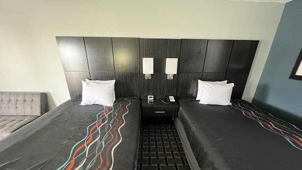 Una habitación de hotel con dos camas, cabeceras, mesitas de noche y un teléfono.