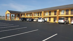 A motel with a covered parking area and multiple vehicles parked.