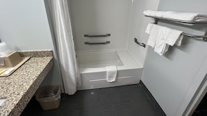 Un baño con ducha, lavabo con encimera y un perchero para toallas.