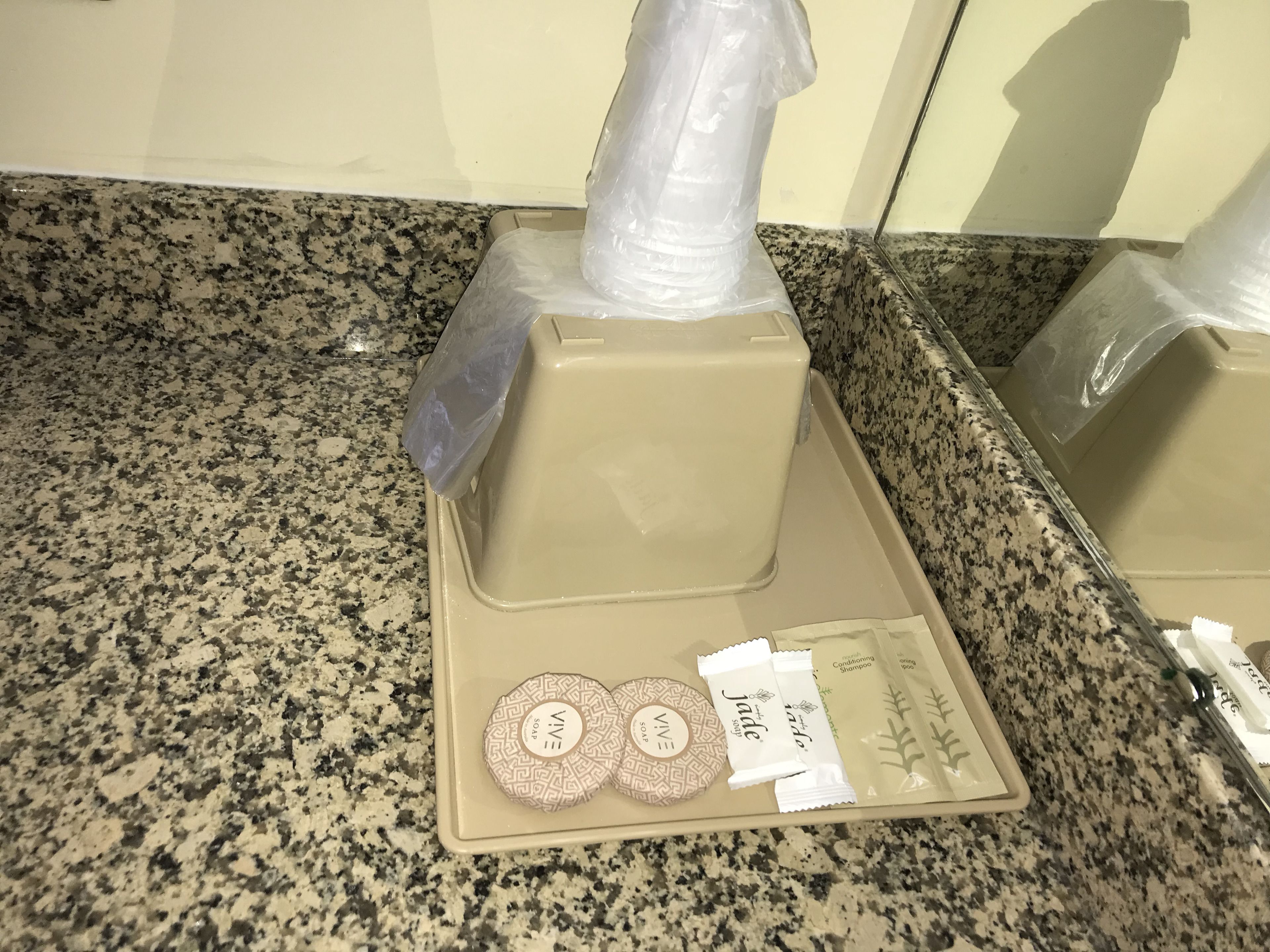 A bathroom counter with a soap dispenser, two soap bars, and a shampoo bottle.