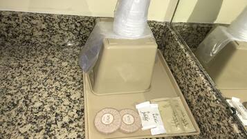 A bathroom counter with a soap dispenser, two soap bars, and a shampoo bottle.