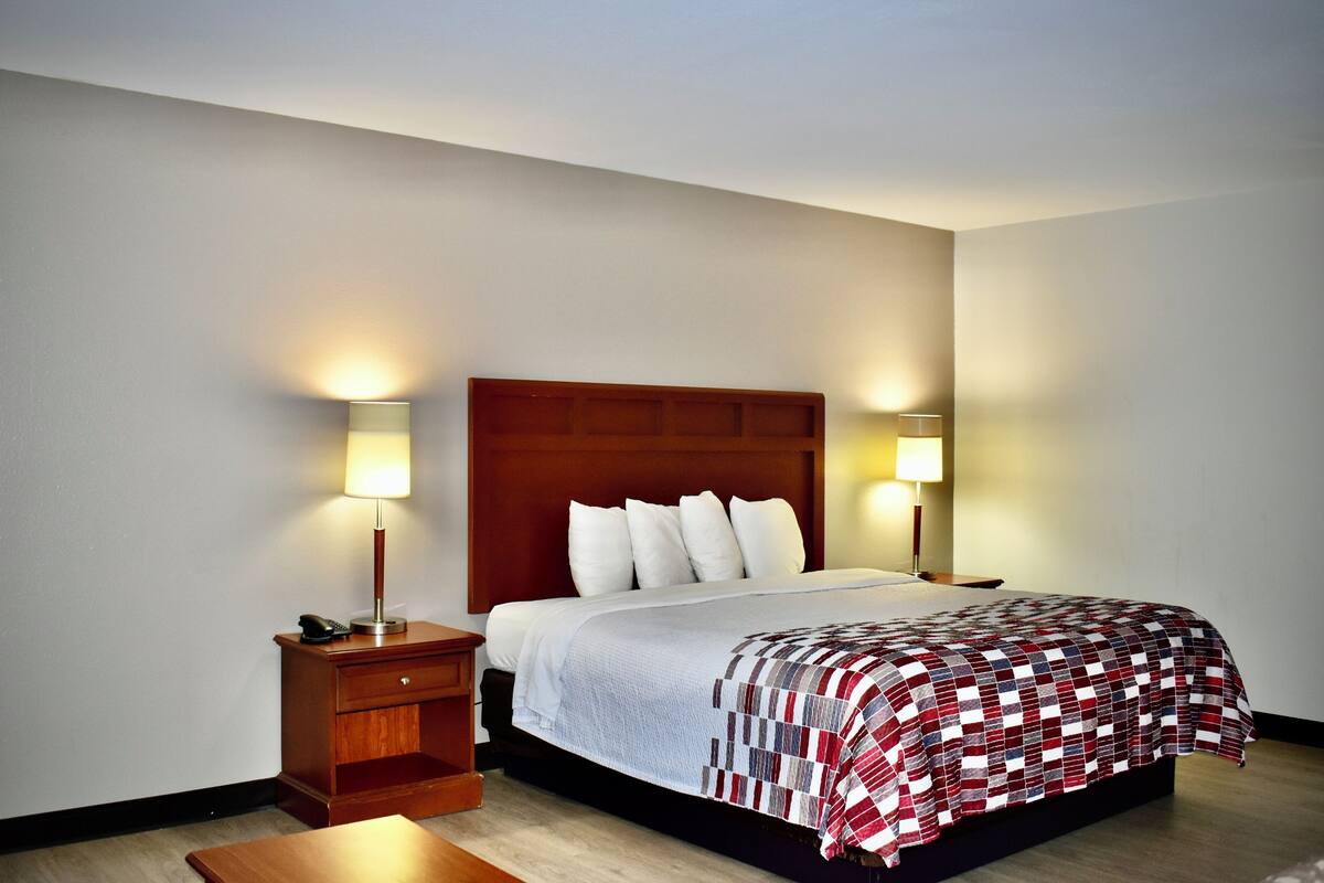 A hotel room with a bed, nightstands, and lamps.