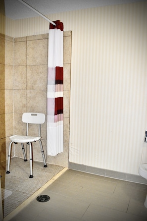 Une salle de bain avec une douche, une chaise blanche et un rideau de douche à rayures.
