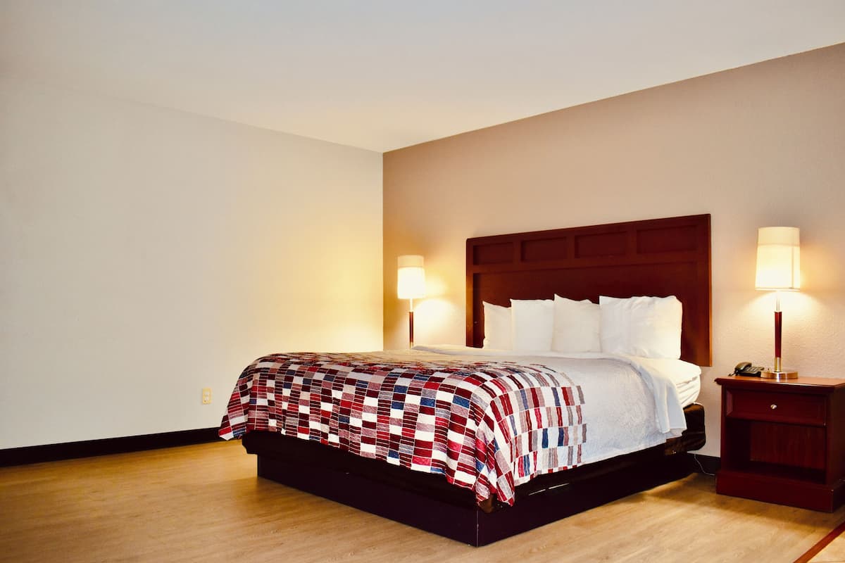 A neatly made bed with a checkered bedspread, a wooden headboard, and two bedside lamps on a wooden nightstand.